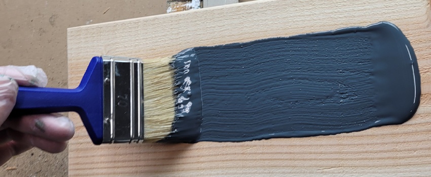 Donkere beits wordt aangebracht op douglas hout met een blokkwast