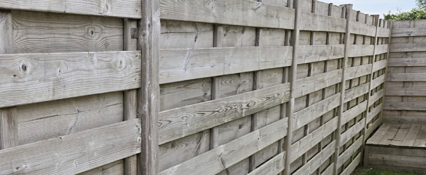 Schutting voorbereiden voor het beitsen Onbehandelde schutting die voorbereid moet worden voor het beitsproces