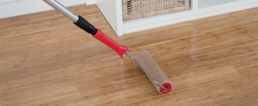 Harwax olie wordt met een roller op een houten vloer aangebracht Harwax olie wordt met een roller op een houten vloer aangebracht