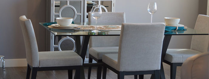 Een gedekte keukentafel met stoelen eromheen voor een muur die behandeld is met muurverf